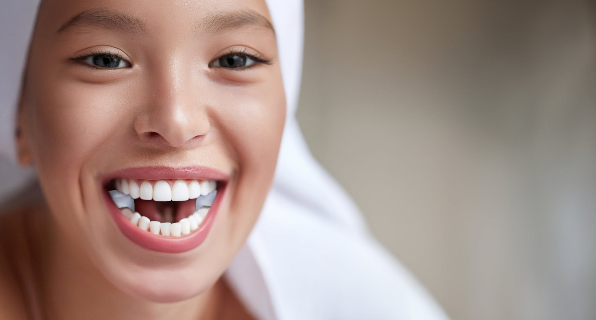 Abbildung einer jungen Frau mit lächelndem Mund. Zwischen den Backenzähnen trägt sie die TJ-Motion - zwei kleine Zahnaufsatzkissen aus medizinischem Silikon. 