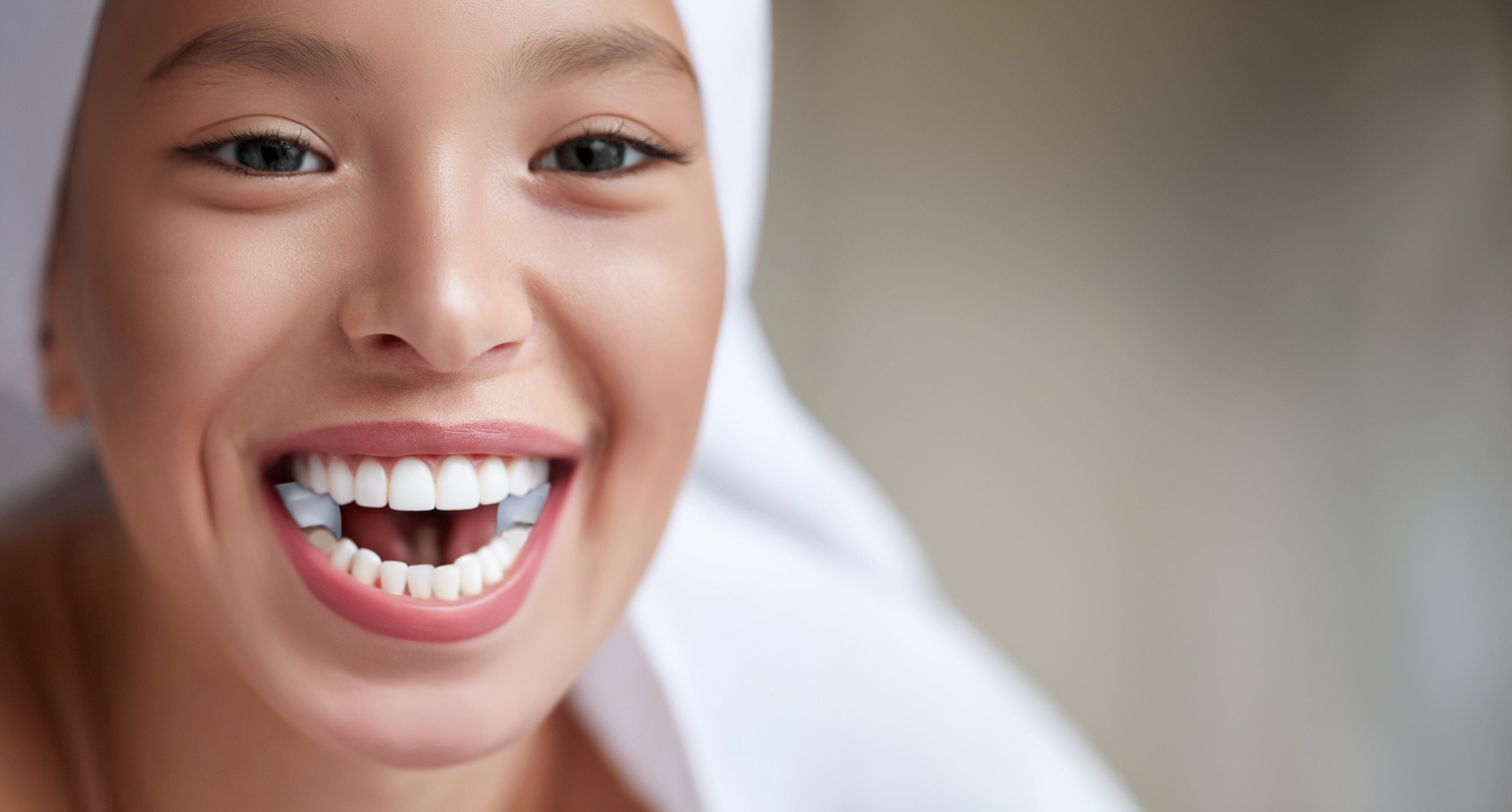 Abbildung einer jungen Frau mit lächelndem Mund. Zwischen den Backenzähnen trägt sie die TJ-Motion - zwei kleine Zahnaufsatzkissen aus medizinischem Silikon. 